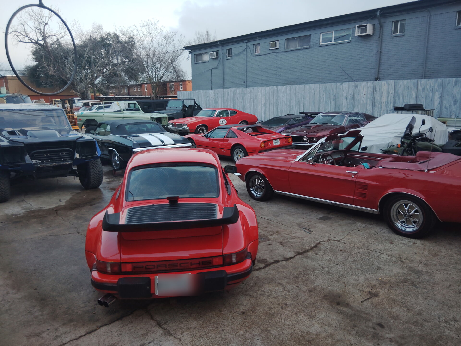 Porsche 911 Turbo, classic Mustangs, and a Ferrari 308 in the Symphonia Werks lot in Houston